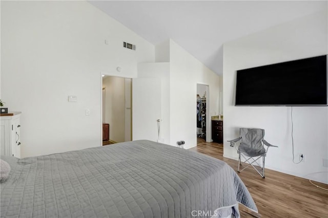 bedroom featuring high vaulted ceiling, a spacious closet, and light hardwood / wood-style floors