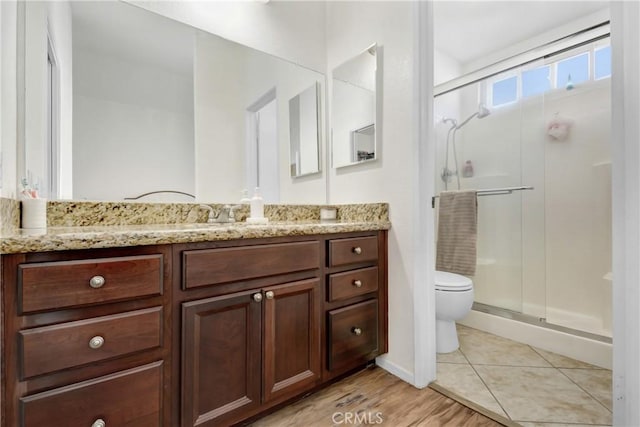 bathroom featuring tile patterned floors, vanity, toilet, and a shower with door