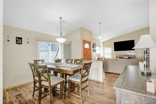 dining area featuring vaulted ceiling, a healthy amount of sunlight, and light hardwood / wood-style floors