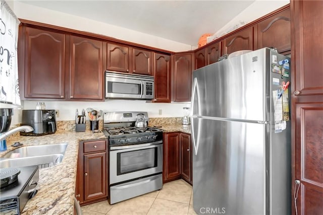 kitchen featuring light stone counters, sink, light tile patterned floors, and stainless steel appliances