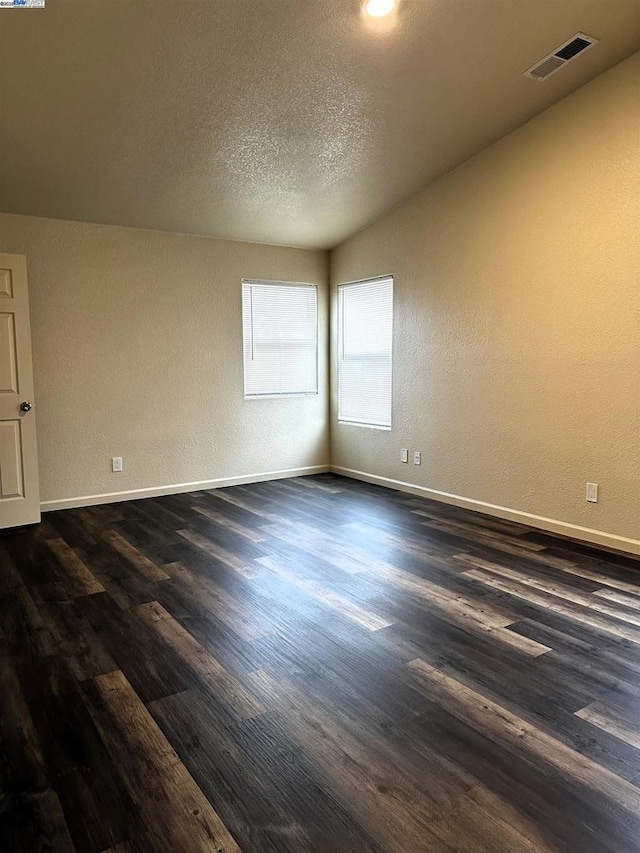 unfurnished room featuring dark hardwood / wood-style flooring and a textured ceiling