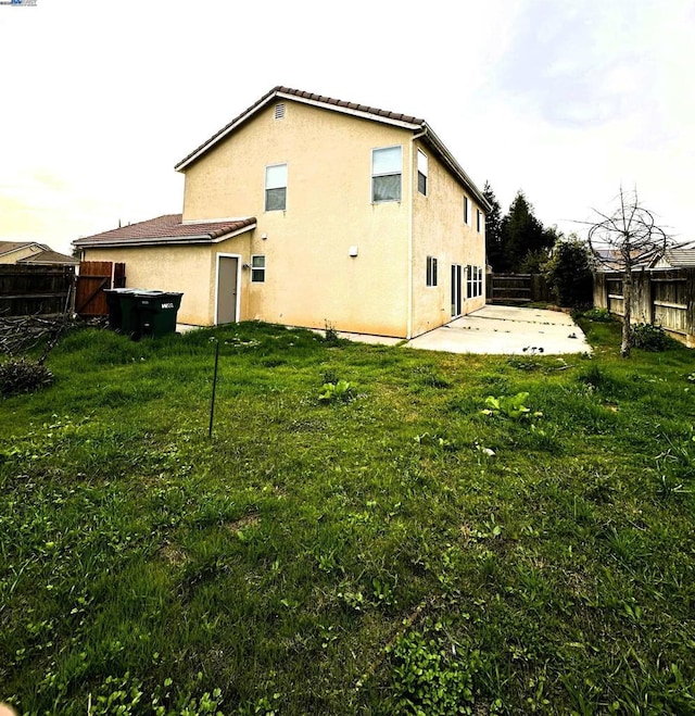 back of house with a lawn and a patio