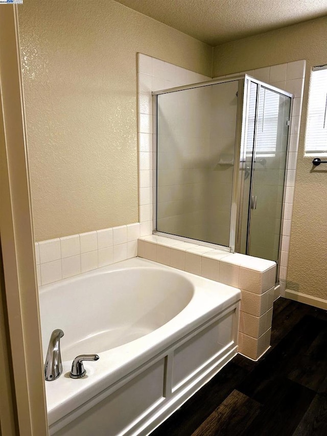 bathroom featuring hardwood / wood-style floors, shower with separate bathtub, and a textured ceiling