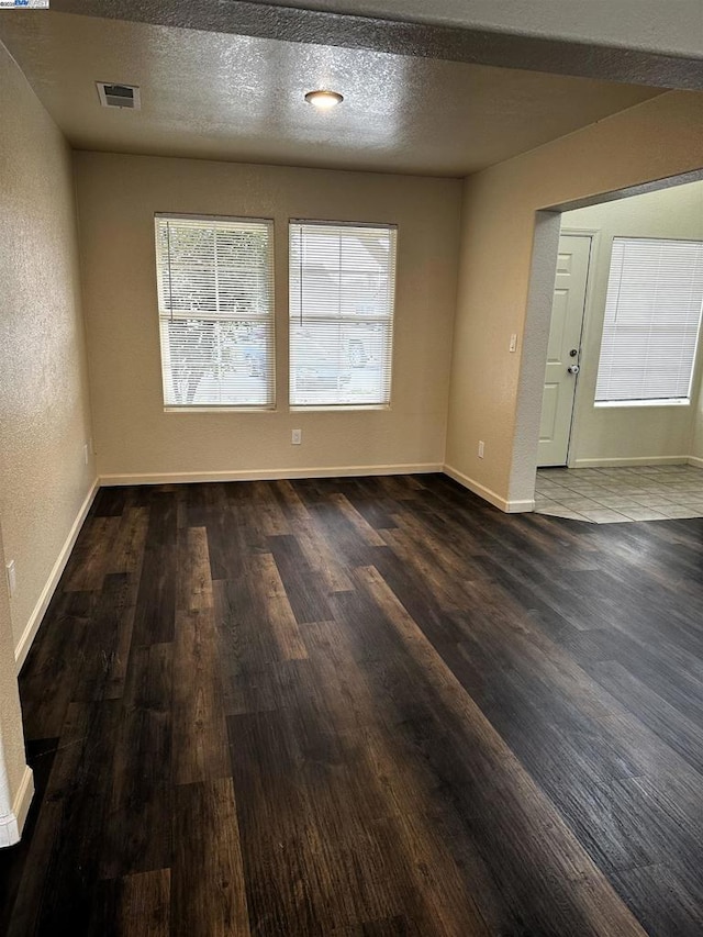 spare room featuring dark hardwood / wood-style floors and a textured ceiling