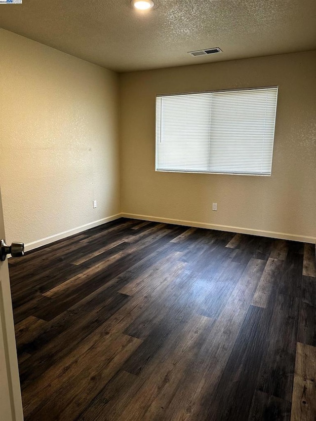 empty room featuring dark hardwood / wood-style floors and a textured ceiling