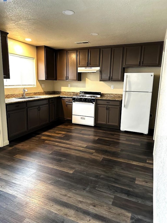 kitchen with dark brown cabinetry, sink, a textured ceiling, dark hardwood / wood-style floors, and white appliances