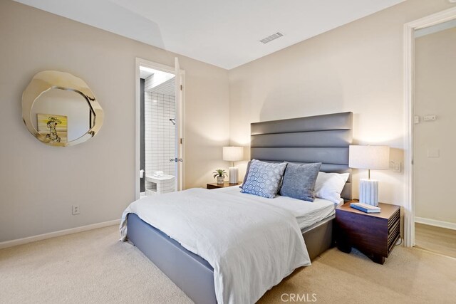 bedroom featuring light colored carpet and ensuite bath