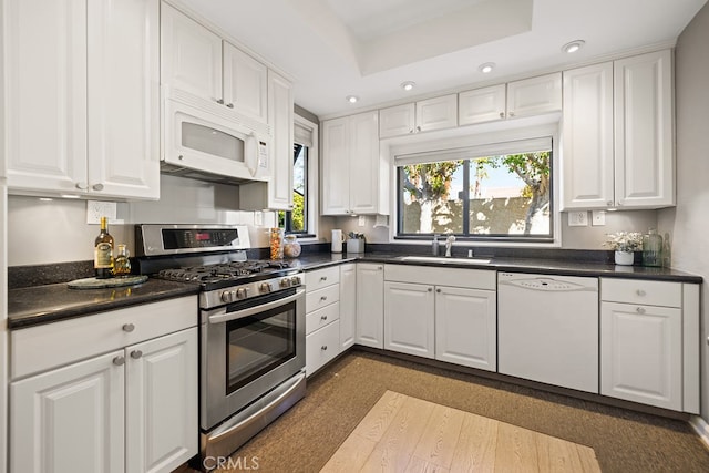 kitchen featuring a raised ceiling, sink, white cabinets, and white appliances