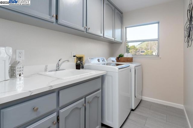 laundry area featuring sink, cabinets, and washer and dryer