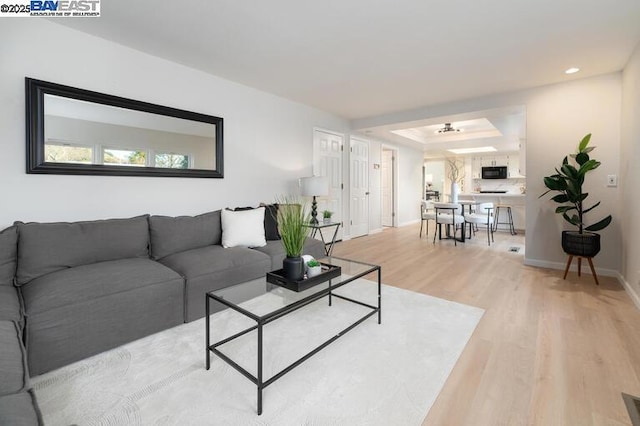 living room featuring a raised ceiling and light wood-type flooring