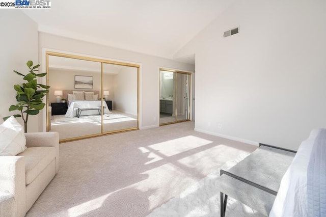 unfurnished bedroom featuring carpet flooring, two closets, and high vaulted ceiling