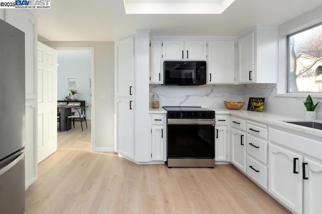 kitchen featuring white cabinetry, stainless steel fridge, light wood-type flooring, and electric stove