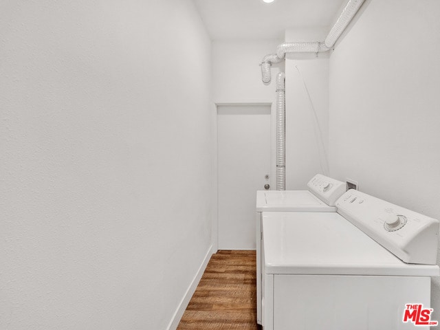 clothes washing area featuring hardwood / wood-style flooring and washing machine and dryer