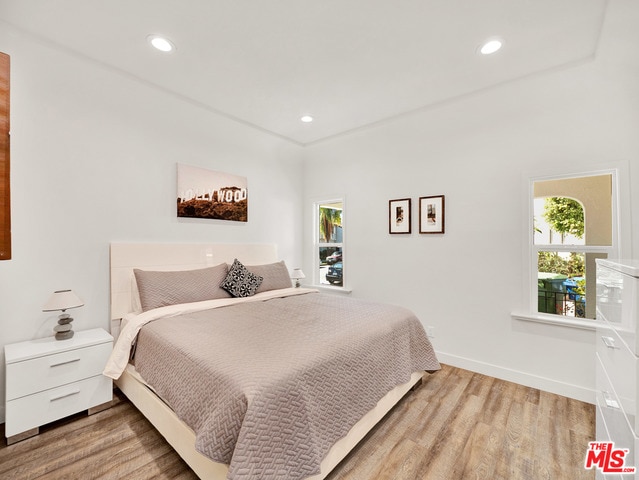 bedroom with multiple windows and light wood-type flooring