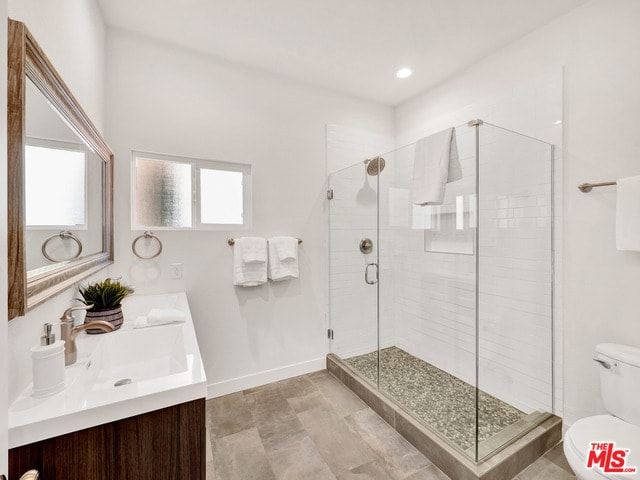 bathroom featuring vanity, an enclosed shower, and toilet