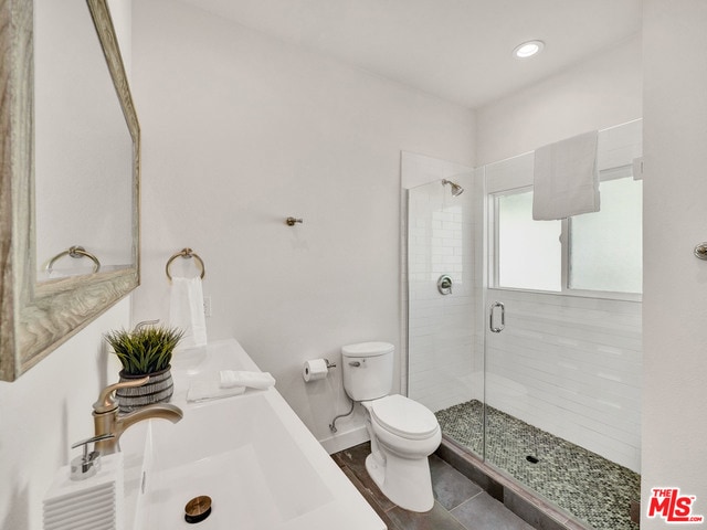 bathroom featuring walk in shower, vanity, tile patterned floors, and toilet