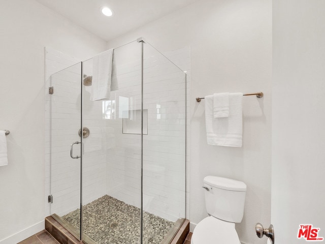 bathroom with toilet and a shower with shower door