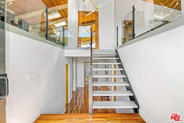 staircase featuring hardwood / wood-style flooring, beamed ceiling, and a high ceiling