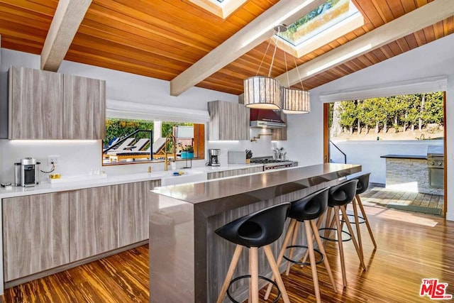 kitchen featuring a breakfast bar area, stove, a center island, vaulted ceiling with skylight, and light hardwood / wood-style floors