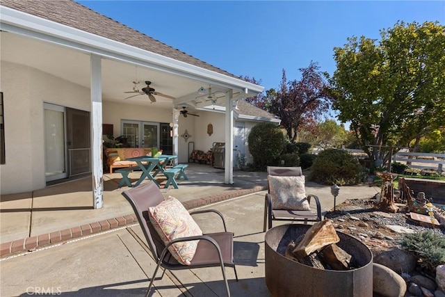 view of patio / terrace with an outdoor fire pit, ceiling fan, grilling area, outdoor dining area, and french doors