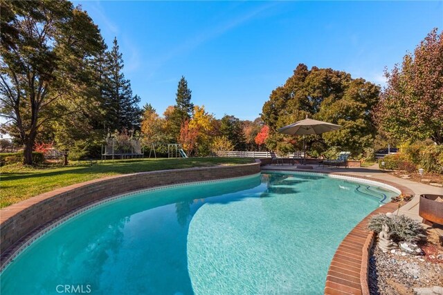 outdoor pool featuring a playground, fence, a yard, a trampoline, and a patio area