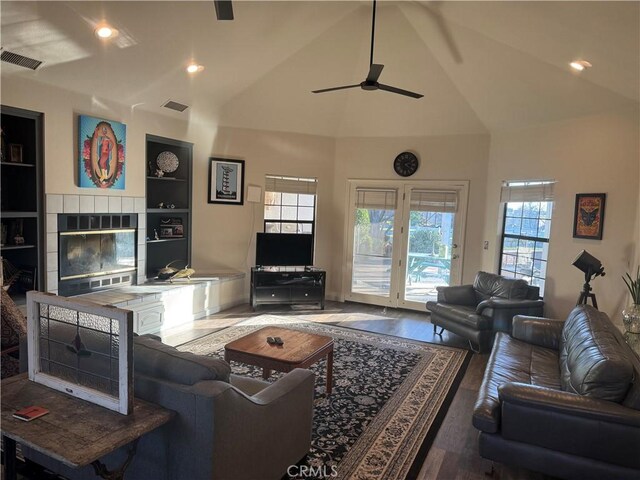 living room with built in shelves, visible vents, a fireplace, and wood finished floors