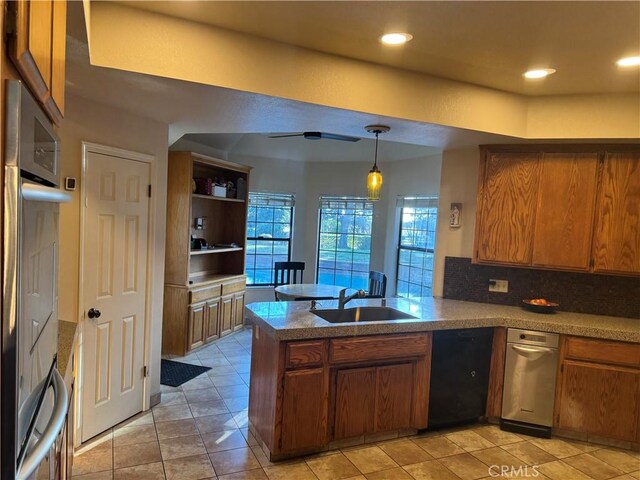 kitchen featuring brown cabinets, a peninsula, a sink, pendant lighting, and backsplash