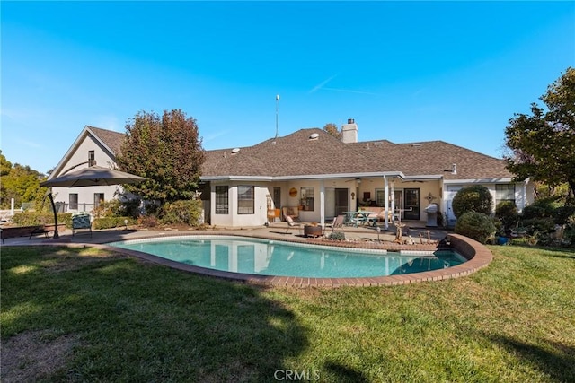 back of house featuring an outdoor pool, a patio, ceiling fan, a chimney, and a yard