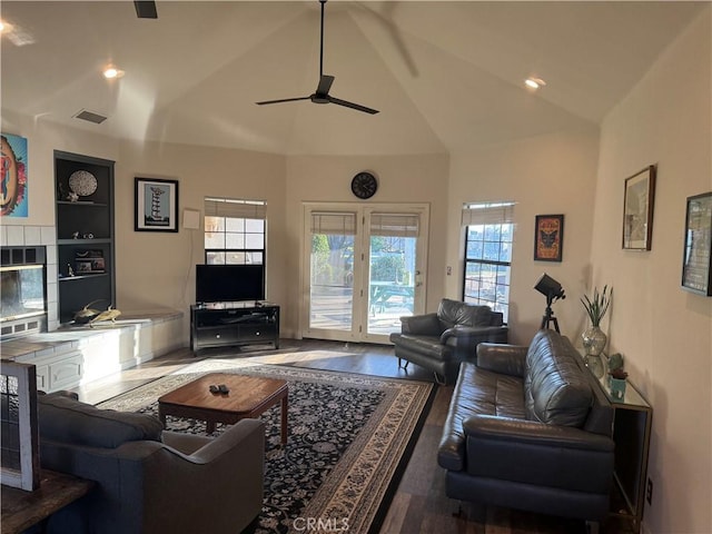 living room with visible vents, built in features, a ceiling fan, wood finished floors, and a fireplace