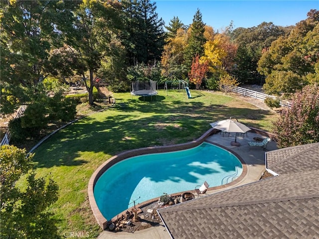 pool with a trampoline, a playground, a patio, a lawn, and fence