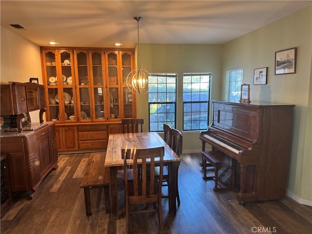 dining area with dark wood-style floors, baseboards, visible vents, and an inviting chandelier