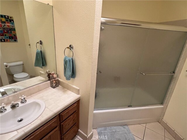 full bath featuring baseboards, toilet, enclosed tub / shower combo, tile patterned floors, and vanity