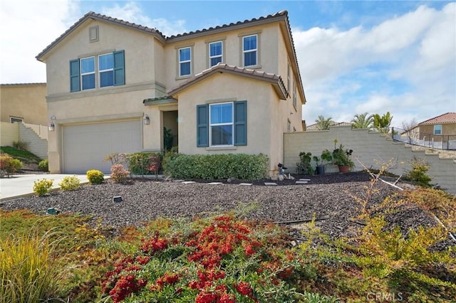 mediterranean / spanish house with a garage, fence, and stucco siding