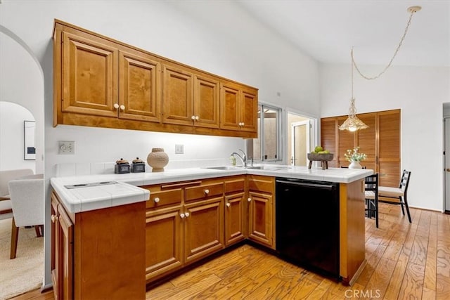 kitchen with dishwasher, sink, hanging light fixtures, kitchen peninsula, and light wood-type flooring