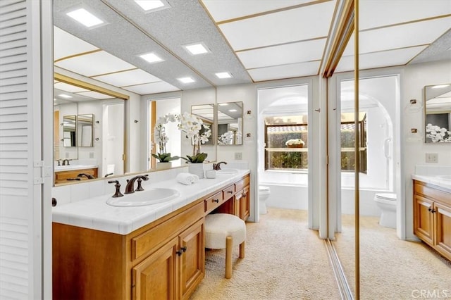 bathroom featuring vanity, a tub, and toilet