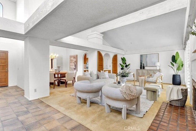 living room featuring a notable chandelier, a brick fireplace, and vaulted ceiling with beams