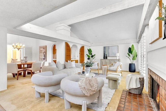 living room featuring vaulted ceiling with beams, an inviting chandelier, and a fireplace