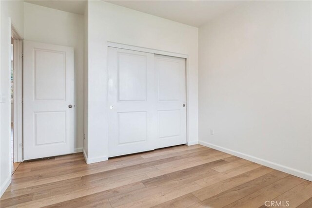 unfurnished bedroom featuring light hardwood / wood-style floors and a closet