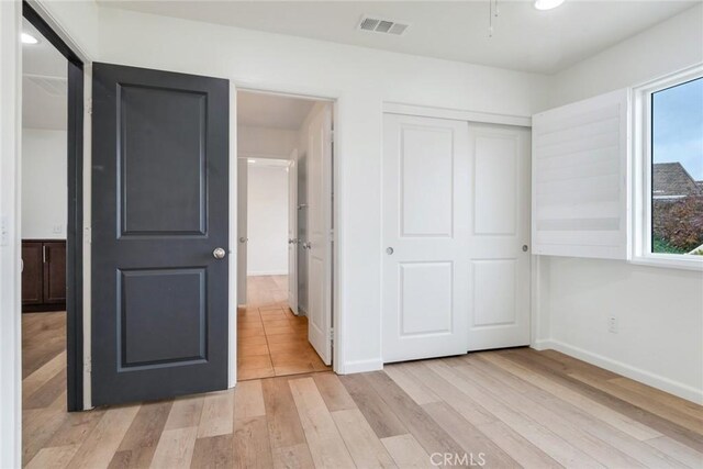 unfurnished bedroom featuring light hardwood / wood-style floors and a closet