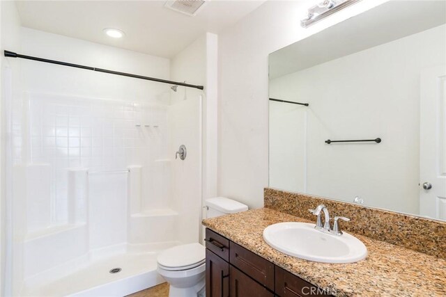 bathroom with walk in shower, vanity, and toilet