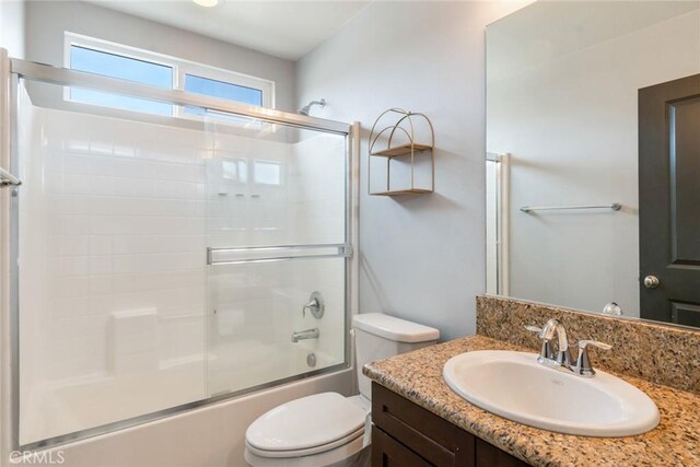 full bathroom with vanity, bath / shower combo with glass door, and toilet