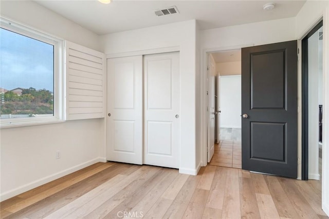 unfurnished bedroom featuring light hardwood / wood-style floors and a closet