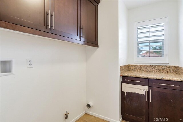 clothes washing area featuring gas dryer hookup and cabinets