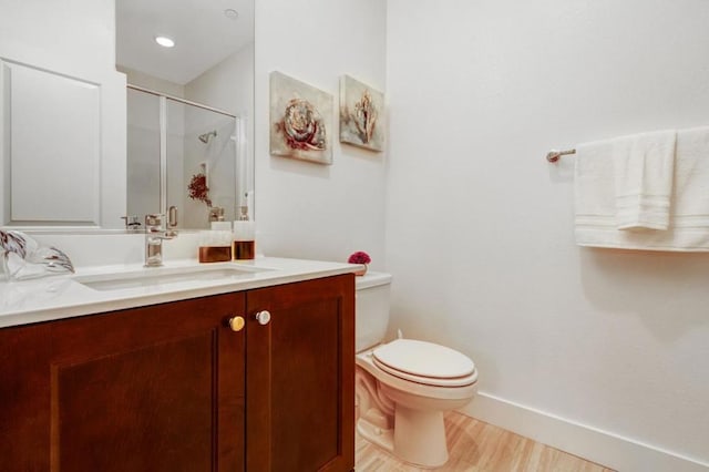 bathroom with vanity, toilet, a shower with shower door, and hardwood / wood-style floors