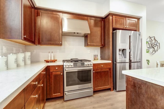 kitchen with light hardwood / wood-style flooring, stainless steel appliances, light stone countertops, decorative backsplash, and wall chimney exhaust hood