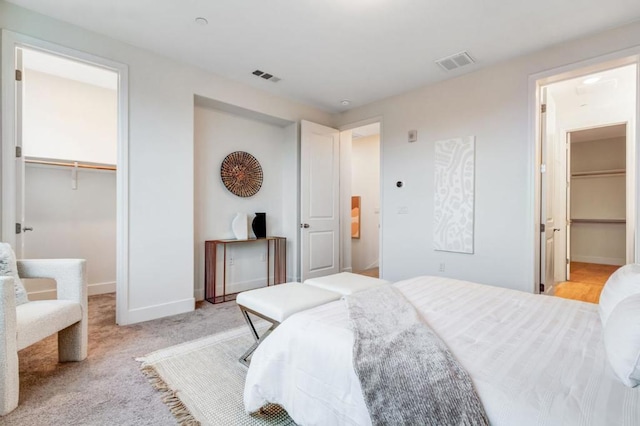 carpeted bedroom featuring a walk in closet and a closet