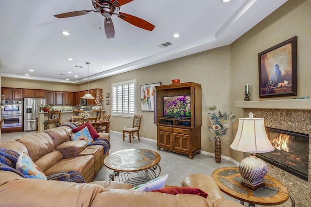 tiled living room featuring ceiling fan and a high end fireplace