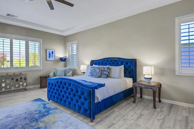 bedroom featuring multiple windows, hardwood / wood-style flooring, and ceiling fan