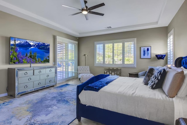 bedroom featuring hardwood / wood-style floors, a raised ceiling, and ceiling fan