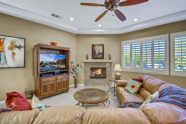 tiled living room featuring a wealth of natural light, a raised ceiling, and ceiling fan